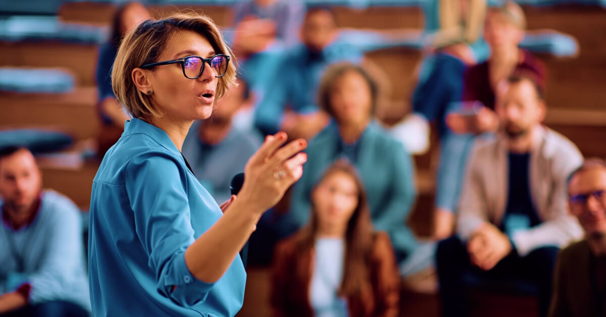 Femme portant des lunettes parlant à un public.